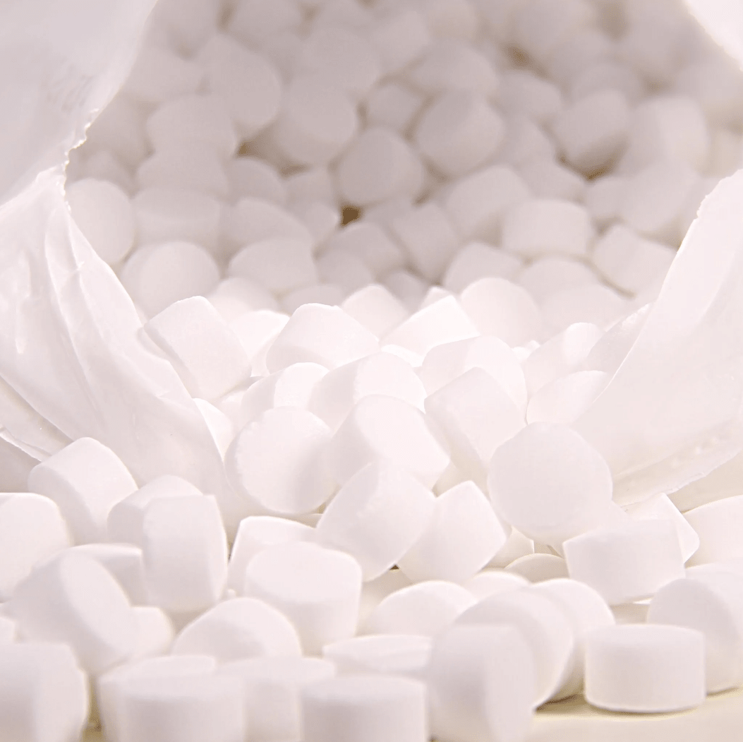 O imagine în prim-plan prezintă o pungă de plastic albă cu inscripția „K+S Minerals and Agriculture GmbH”, care conține tablete de sare de evaporare Regenit conform standardului EN 973, tip | sac (25 kg), care cad pe o suprafață. Tabletele mici și rotunde au o formă și o dimensiune uniforme și sunt ideale pentru utilizarea în instalațiile de dedurizare a apei.