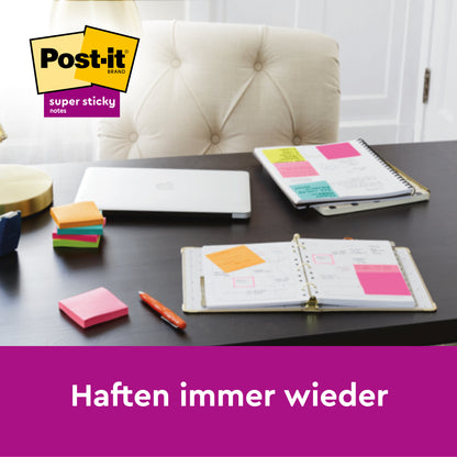 Un birou cu caiete deschise, acoperite cu Post-it® Super Sticky Notes colorate (63,5 x 76 mm, 90 foi/bloc, 8 blocuri/cutie, certificat PEFC) de la 3M Deutschland GmbH. Un teanc de notițe adezive, un stilou, un laptop și o lampă completează scena.