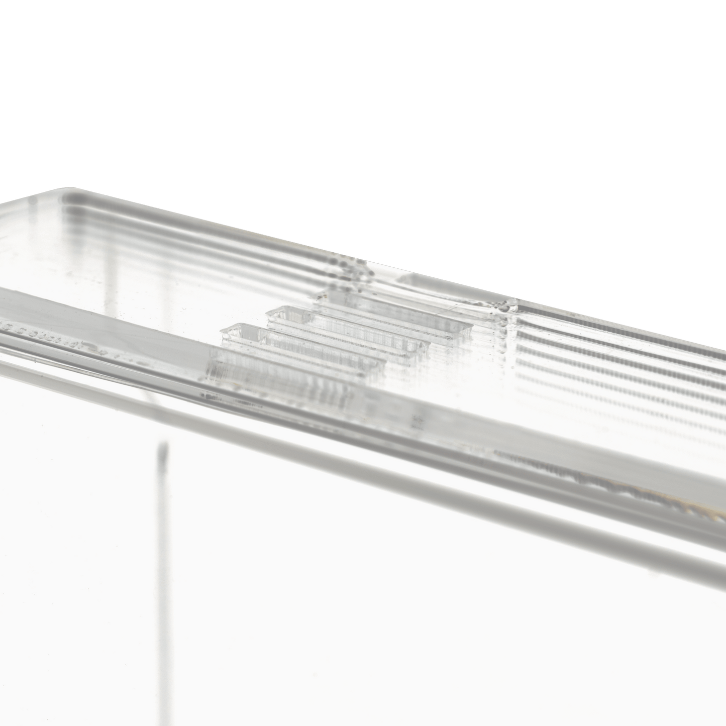Prim-plan al dispenserului transparent, lăptos, pentru mănuși de unică folosință (250 x 135 x 55-90 mm) de la AMPri Handelsgesellschaft mbH, un suport dreptunghiular din acril cu margini canelate pe un fundal alb simplu.