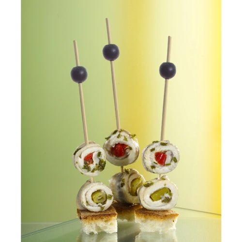 Trei PAPSTAR 250 de scobitori Fingerfood ale PAPSTAR GmbH țin brioșe cu brânză, ierburi și legume pe cuburi de pâine, fiecare garnisită cu o măslină neagră. Fundalul iluminat ușor este în tonuri de verde și galben.