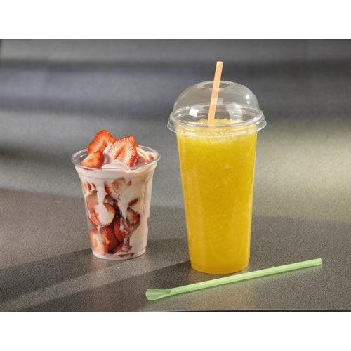 Un pahar transparent cu parfait de căpșuni, căpșuni tăiate și iaurt este așezat lângă un pahar înalt pentru smoothie Starpak din PET clar, cu un capac dom Starpak 50 „Hurricane” (rotund, Ø 9,5 cm – 4,5 cm); pe suprafața gri se află un băț verde pentru amestecare.