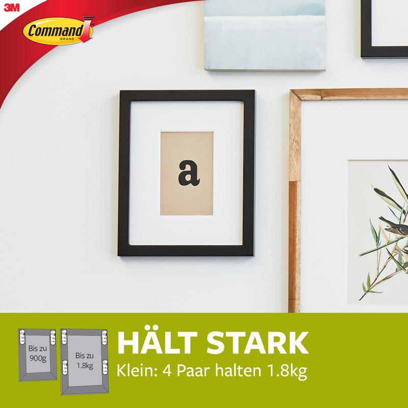 Printre altele, un imprimeu "a" este agățat într-o ramă neagră. Partea inferioară verde arată benzi de montare pentru imagini Command™ mici albe S 17202FGN de la 3M Deutschland GmbH: fixare invizibilă, rezistență puternică, 4 perechi suportă până la 1,8 kg fără urme.