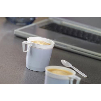 Două căni de cafea Starpak (0,25 l, alb, PS) din pachetul de 40 sunt umplute pe gri; alături o linguriță de plastic alb și în fundal o tastatură de laptop ca indiciu pentru consumul zilnic de cafea.