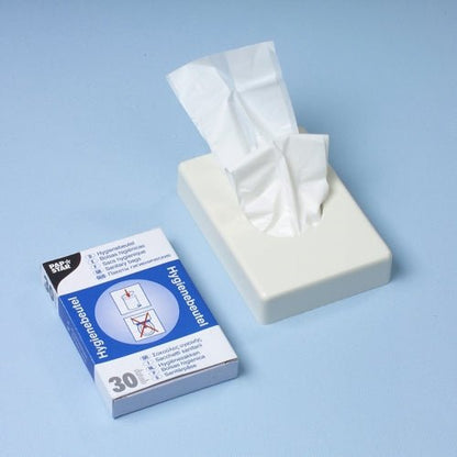 Un distribuitor alb de batiste se află lângă o cutie distribuitoare Starpak de 30 de pungi igienice (28,5 x 8 x 7 cm, alb), care conține 30 de pungi igienice cu imagini de instrucțiuni pe o suprafață albastru deschis.
