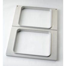 Caseta Duni GmbH DF15/25 pentru tăvi CPET 960-1500 ml - cu 2 utilizări este un cadru metalic dreptunghiular cu două deschideri dispuse vertical, finisaj periat și margini rotunjite - perfect pentru depozitarea tăvilor CPET pe orice suprafață albă.