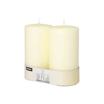 Două lumânări Starpak, Ø 80 mm, cu cap plat, stau în suportul simplu de carton cu etichetă – o notă de eleganță atemporală pentru orice ambianță.