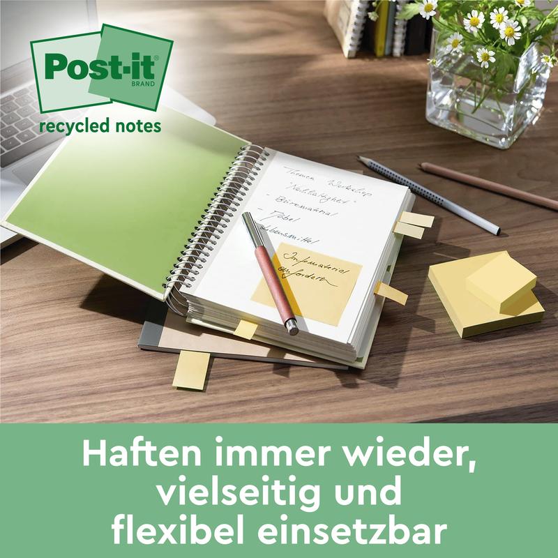 Un caiet spiral cu notițe Post-it® Recycling (38 mm x 51 mm, 100 foi/bloc, 100% PEFC, de la 3M Deutschland GmbH) este deschis pe un birou lângă un stilou, un caiet închis, blocuri de notițe adezive și un recipient de sticlă cu plante verzi. Text în germană dedesubt.
