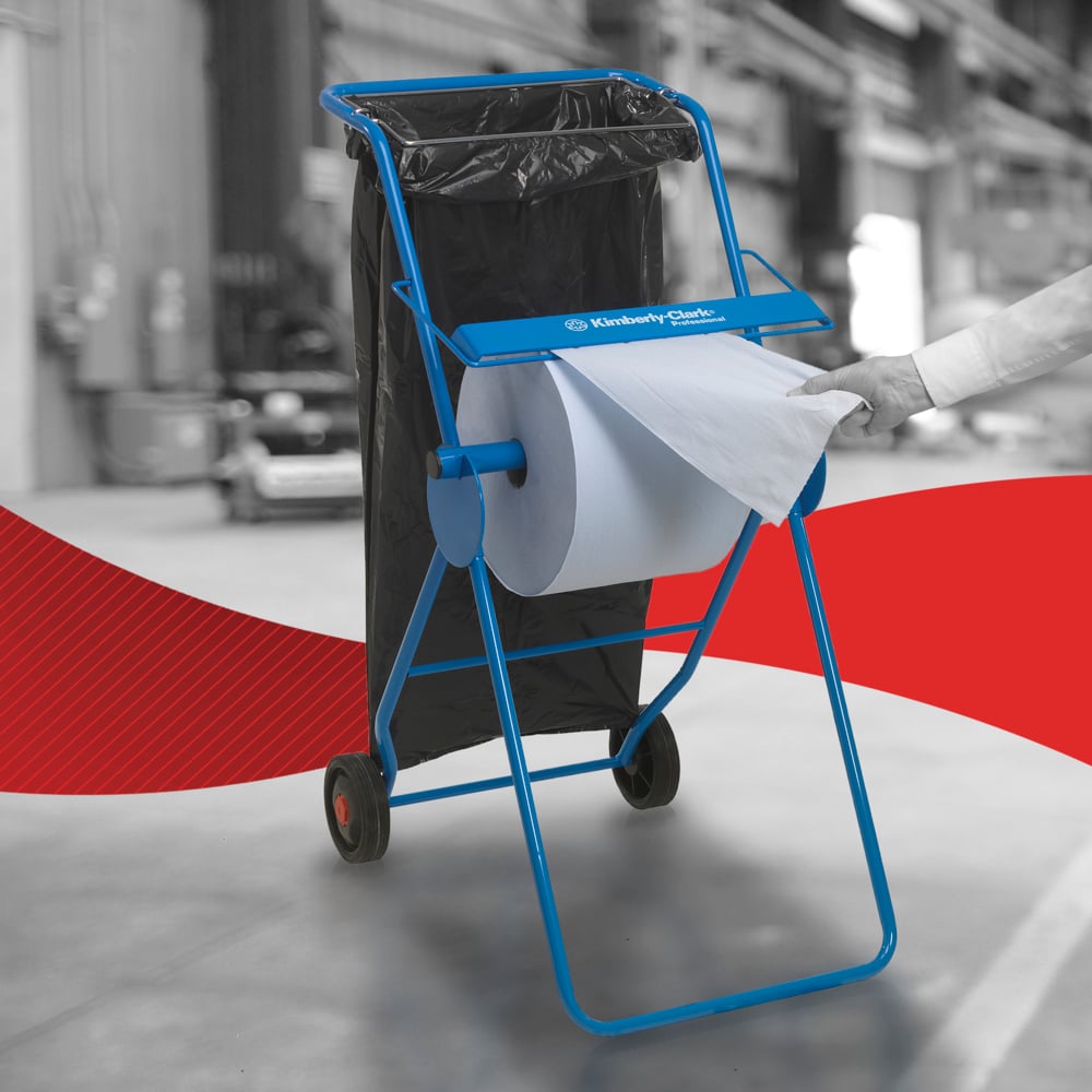 O persoană scoate un șervețel de hârtie WypAll® L20 pentru întreținere - rolă mare / albastră de la Kimberly-Clark GmbH dintr-un distribuitor albastru într-un mediu industrial, cu logo-ul Kawasaki Robotics și un sac de gunoi negru în apropiere.