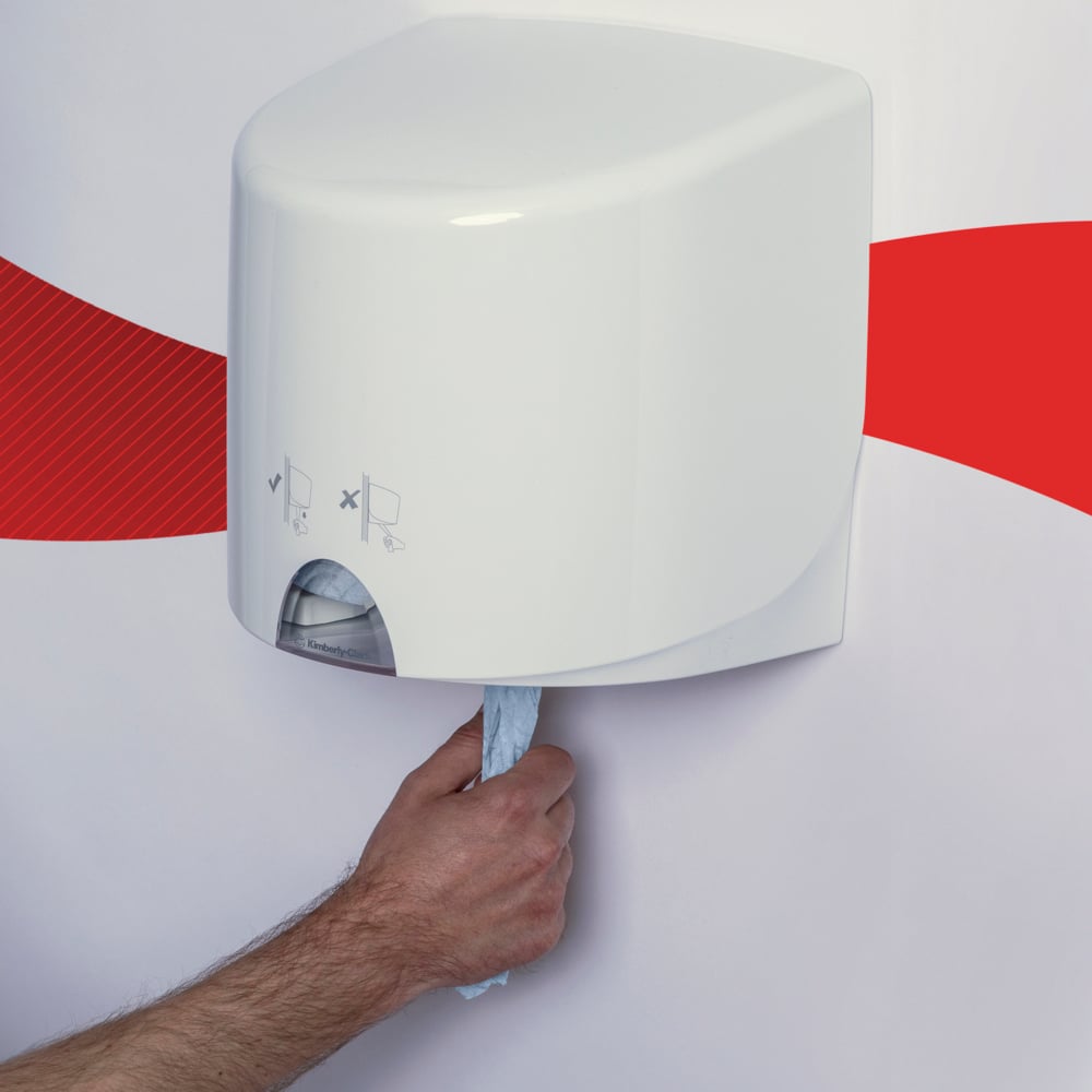 O mână trage un șervețel de hârtie albastru WypAll® L10 pentru alimente și igienă de la Kimberly-Clark GmbH dintr-un distribuitor alb montat pe perete, în fața unui perete alb cu o bandă ondulată roșie.
