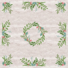 Ein heller Holzhintergrund mit grüner, belaubter Tischdekoration in jeder Ecke und einem kreisförmigen Kranz aus Grünzeug und roten Beeren erinnert an die festliche, wasserabweisende Dunisilk(Plus)-Mitteldecke 84x84 der Duni GmbH.