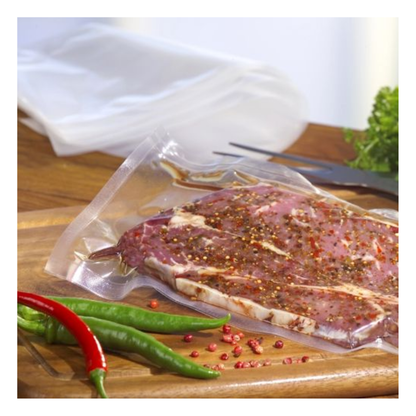 O friptură crudă, marinată este vidată într-o pungă transparentă Starpak 100 Siegelrandbeutel (PA/PE) cu un aparat de vidat cu cameră pe un tocător din lemn, cu ardei iuți, boabe de piper roz, legume cu frunze și o furculiță în fundal.