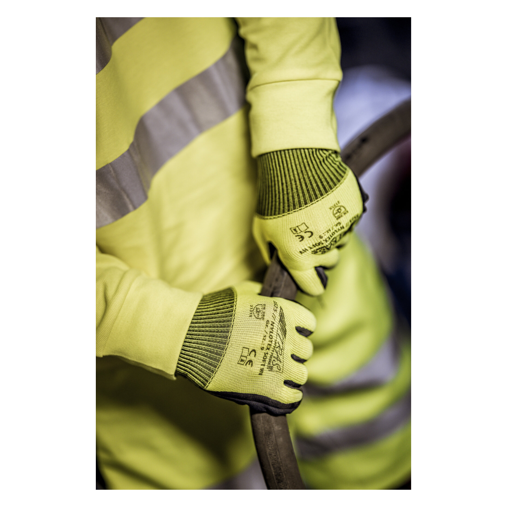 O persoană care poartă o vestă de avertizare galbenă și mănuși din nailon NITRAS NYLOTEX SOFT HV de la AS Arbeitsschutz GmbH, galben neon, parțial acoperite – cu text negru și simboluri de siguranță – ține un cablu sau un furtun gros și întunecat.