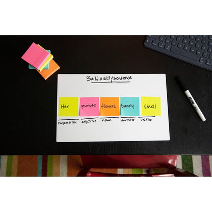 Un cub de note Post-it® al 3M Deutschland GmbH (76x76mm, 450 foi, 100% PEFC) arată un exercițiu de construcție a propozițiilor pe un tablă albă cu etichete gramaticale; note adezive suplimentare, un marker, o tastatură și un covor dungat sunt în apropiere.