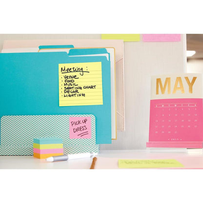 Un birou cu dosare colorate, un teanc de notițe adezive și un calendar roz-auriu pentru mai 2017. Pe Post-it® Super Sticky Notes (101 mm x 101 mm, 90 foi, PEFC) de la 3M Deutschland GmbH sunt subiecte de întâlnire și "PICK UP DRESS".