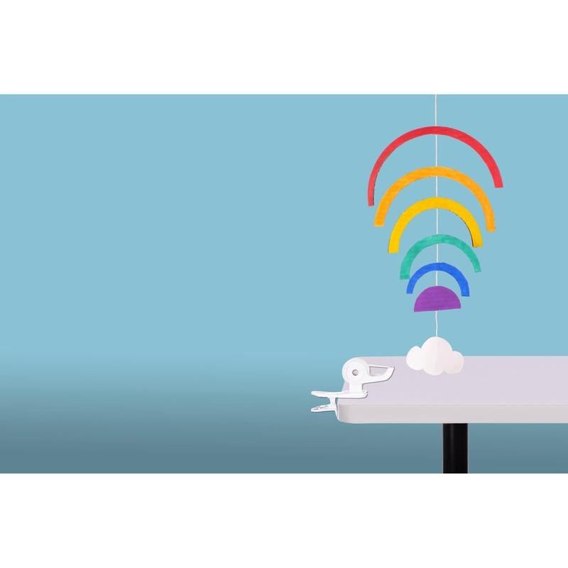 Un mobil din hârtie colorată cu cinci curcubee și un nor alb este agățat de marginea unei mese albe, asigurat de dispenserul de bandă adezivă Scotch™ Clip & Twist C19 cu bandă Magic™ de la 3M Deutschland GmbH, pe un fundal albastru deschis.