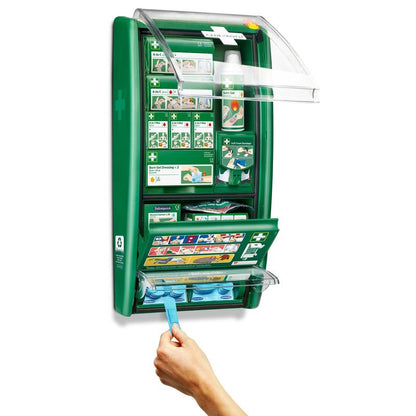 Stația de prim ajutor și arsuri Cederroth de la Orkla Wound Care AB este un set verde montat pe perete, cu compartimente etichetate pentru bandaje, pansamente și gel pentru arsuri. O mână trage o cârpă albastră din unitatea deschisă și dezvăluie provizii ordonate și instrucțiuni clare.