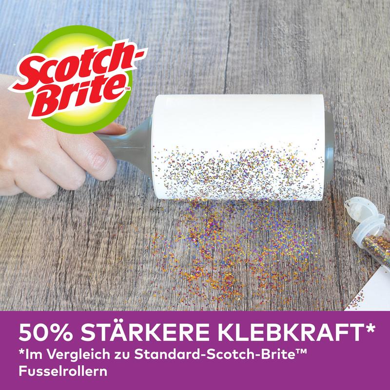 O mână folosește rollerul pentru părul de animale Scotch-Brite™ Pet Extra Sticky* de la 3M Deutschland GmbH (48 de foi) pentru a îndepărta sclipiciul vărsat de pe o suprafață de lemn. Publicitate germană: putere de aderare cu 50% mai mare decât modelele standard.