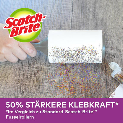 O mână folosește rollerul pentru părul de animale Scotch-Brite™ Pet Extra Sticky* de la 3M Deutschland GmbH (48 de foi) pentru a îndepărta sclipiciul vărsat de pe o suprafață de lemn. Publicitate germană: putere de aderare cu 50% mai mare decât modelele standard.