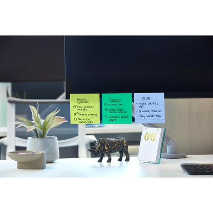 Un monitor de computer cu Post-it® Super Sticky Notes (101 mm x 101 mm, 90 foi, 100% PEFC) de la 3M Deutschland GmbH, pe care sunt listate actualizări de site și sarcini de făcut. În apropiere: o plantă în ghiveci, o figurină de rinocer negru, un calendar de birou cu data "06" și un bol cu agrafe de birou.