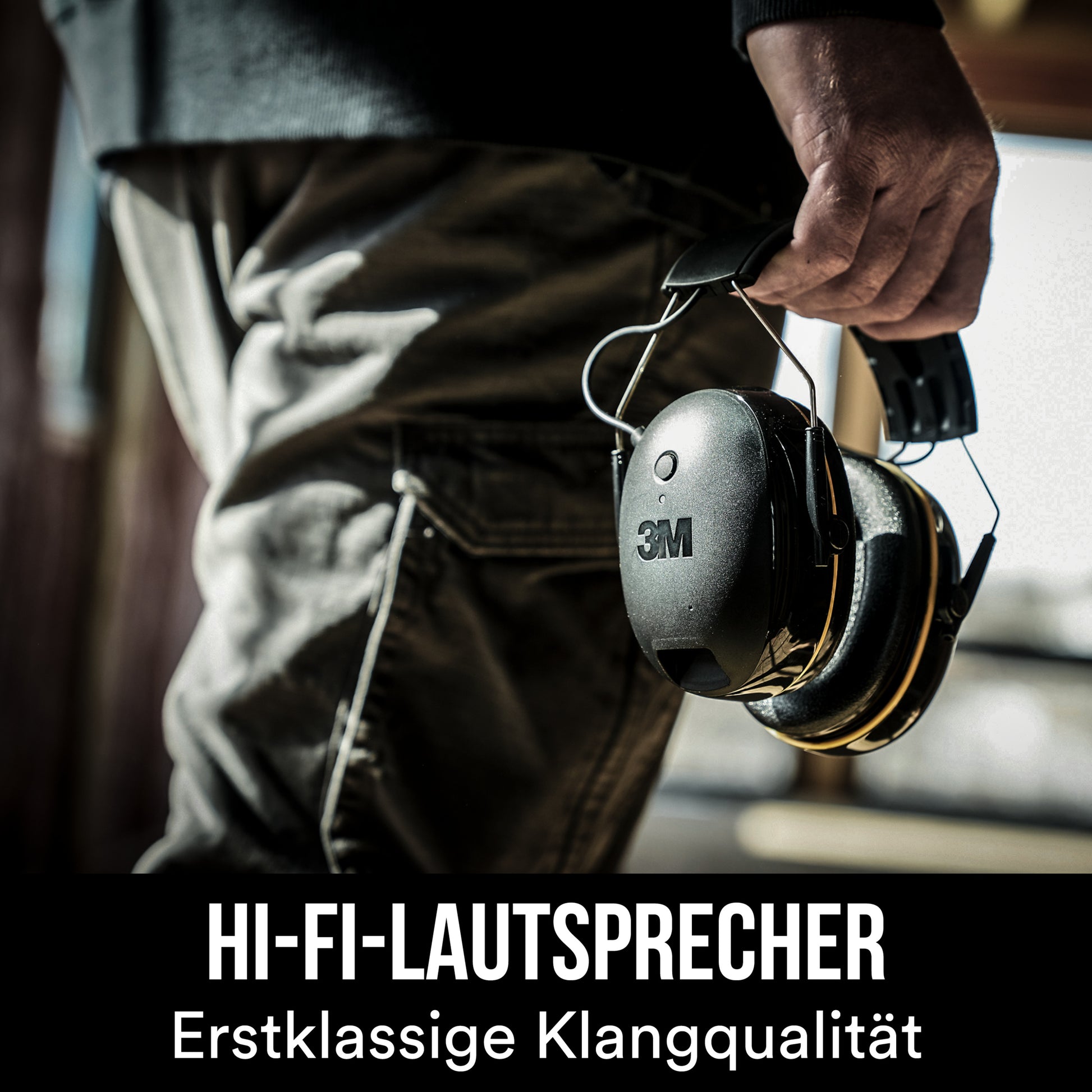 Eine Person hält einen schwarzen 3M™ WorkTunes™ Connect Kapselgehörschutz 90543E Bluetooth® (SNR 31 dB) von 3M Deutschland GmbH. Der Text darunter lautet auf Deutsch "HI-FI-LAUTSPRECHER Erstklassige Klangqualität".