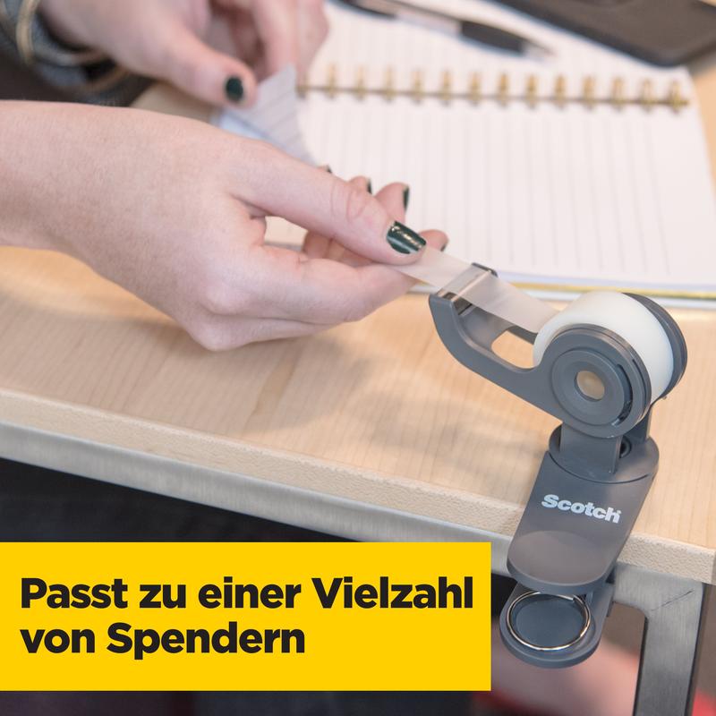O persoană trage banda invizibilă Scotch® Magic™ de la 3M Deutschland GmbH dintr-un suport de bandă gri pe un birou de lemn, cu un carnet și un stilou în fundal. Textul german spune: „Se potrivește cu o varietate de dispensere.