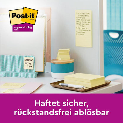 Un spațiu de lucru este echipat cu Post-it® Super Sticky Notes, Galben, 76 mm x 76 mm, 90 foi/pachet de la 3M Deutschland GmbH. Pe perete se află o notă cu inscripția: "Se lipește sigur, se îndepărtează fără reziduuri." Branding-ul este vizibil.