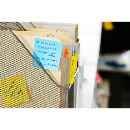Un dosar cu plasă de sârmă ține dosare Manila cu separatoare colorate și etichete scrise de mână. Un cub albastru de note Post-it® (76x76 mm, 450 foi/bloc, 100% PEFC) de la 3M Deutschland GmbH este atașat; alte note adezive apar în fundal.