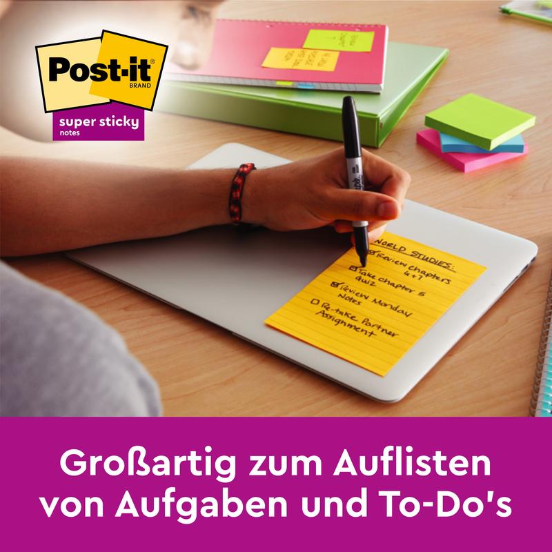 O persoană scrie pe un Post-it® Super Sticky Note galben (101mm x 101mm, 90 foi, 100% PEFC) de la 3M Deutschland GmbH pe un laptop închis; alte articole de birou colorate sunt vizibile. Textul german spune: "Groza pentru listarea sarcinilor și a lucrurilor de făcut.