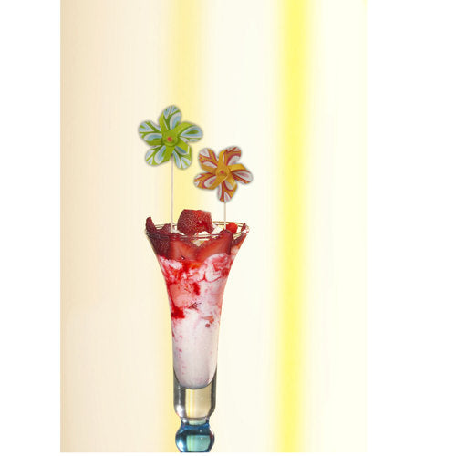 Ein hohes Glas enthält ein rosa-weißes Dessert, gekrönt von Erdbeersauce und einem PAPSTAR Deko-Picker "Windmühle" (17,5 cm, farblich sortiert), der die Partydekoration spielerisch bereichert. Das Set der PAPSTAR GmbH enthält 50 Picker in einer Pappschale.