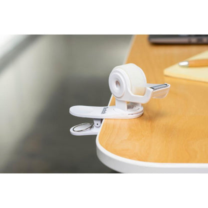 Dispenserul de bandă adezivă Scotch™ Clip & Twist C19 cu bandă invizibilă Scotch® Magic™ (19 mm × 8,89 m) de la 3M Deutschland GmbH este prins de o masă de lemn lângă un blocnotes și un stilou.