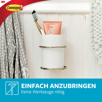 Ein weißer Becher mit Zahnbürste und Zahnpasta ruht in einem Command™ Metall-Haken Bad, schmal, Satin Nickel von 3M Deutschland GmbH; ideal für Badezimmer-Aufbewahrung. Einfach anzubringen - keine Werkzeuge nötig. Haken ohne Bohren.