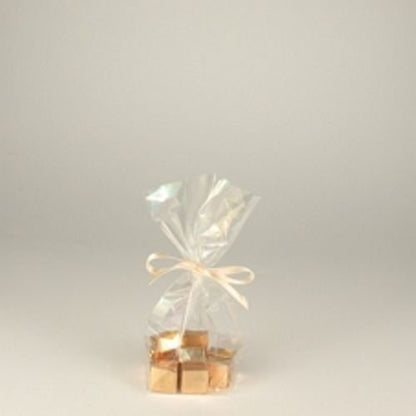 Un PAPSTAR pachet de 300 pungi de bază, celofan „pure“ transparent de la PAPSTAR GmbH, legat cu o panglică deschisă și umplut cu cuburi ambalate în aur, oferă un set de ambalaje biodegradabile și sustenabile pe un fundal simplu și luminos.
