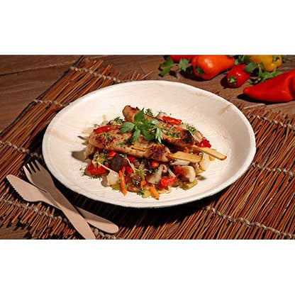 Frigărui de pui la grătar cu o tigaie colorată de legume sunt servite pe o farfurie PAPSTAR 6, frunză de palmier „pure“ rotundă de la PAPSTAR GmbH – veselă ecologică, prezentată cu stil pe un suport țesut cu tacâmuri din lemn și ardei proaspăt în vedere.