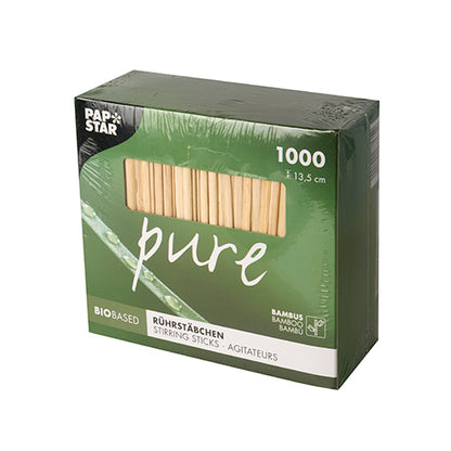 Eine grüne Box mit der Aufschrift „pure“ enthält 1000 PAPSTAR Bambus Rührstäbchen (13,5 cm, biologisch abbaubar). Oben links befindet sich das Logo der PAPSTAR GmbH; Icons weisen auf das umweltfreundliche Bambusmaterial der Verpackung hin.