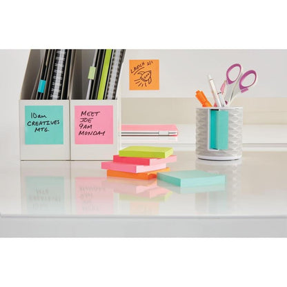 Un birou ordonat cu cuburi colorate de note Post-it® (76x76mm, 450 foi/bloc, 100% PEFC) de la 3M Deutschland GmbH, un suport de stilouri alb, plin cu stilouri și foarfece, caiete și cutii de fișe. Notițele adezive sunt inscripționate cu amintiri scrise de mână.