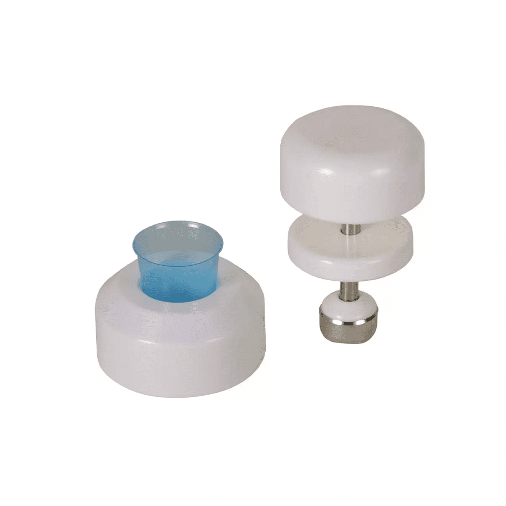 Pe un fundal alb se văd două ustensile de bucătărie albe din plastic. Ustensila din stânga are o formă cilindrică cu un inserție de plastic albastru, în timp ce ustensila din dreapta este un pistil de tablete AMPri pentru pahare de medicamente al AMPri Handelsgesellschaft mbH, care este format din două discuri albe conectate printr-o tijă de oțel inoxidabil cu o bază metalică.