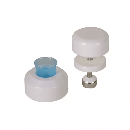 Pe un fundal alb se văd două ustensile de bucătărie albe, din plastic. Ustensila din stânga are o formă cilindrică, cu un insert din plastic albastru, în timp ce ustensila din dreapta este un mojar pentru comprimate AMPri destinat paharelor de medicamente ale societății AMPri Handelsgesellschaft mbH, format din două discuri albe, unite printr-o tijă din oțel inoxidabil cu o bază metalică.