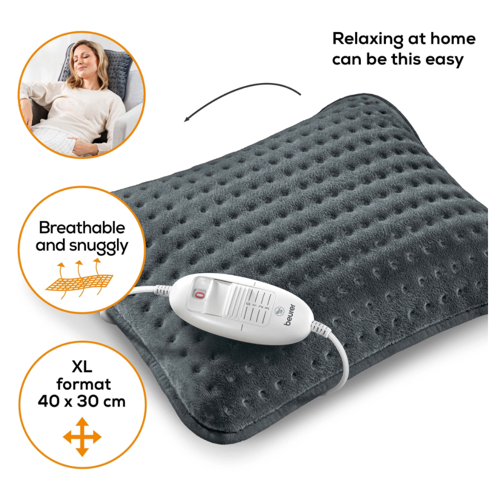O femeie stă întinsă pe o canapea și zâmbește cu ochii închiși. Lângă ea se află o pernă de încălzire pentru canapea Beurer HK 48 Cosy de culoare gri închis cu o unitate de control albă. Pe pernă scrie „Așa de simplu poate fi să te relaxezi acasă”, „Respirabil și confortabil” și „Format XL 40 x 30 cm”.