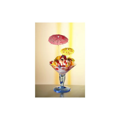 Într-un pahar de sticlă se află un desert colorat cu înghețată, decorat cu bile din cireșe, fructe tăiate și bețe decorative colorate PAPSTAR de la PAPSTAR GmbH. Fundalul ușor iluminat pune în evidență desertul în mod optim.