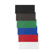 Șase covorașe Arcora HANDPAD - DICK de 250 x 15 cm, produse de Arcora International GmbH, sunt stivuite vertical în culorile negru, maro, verde, albastru, roșu și alb – ideale ca suport pentru mâini sau ca instrument de curățare pentru lustruirea metalului.