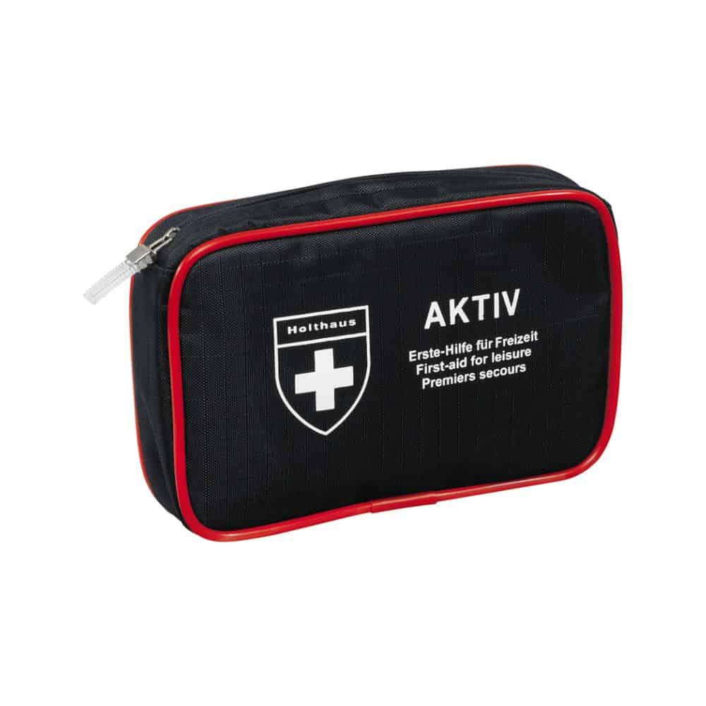 Un set compact de prim ajutor negru cu margine roșie și fermoar, un logo cu cruce albă și textele „Holthaus Medical AKTIV” și „Erste-Hilfe für Freizeit / First-aid for Leisure / Premiers secours” pe partea din față. Perfect pentru călătorii și acasă.