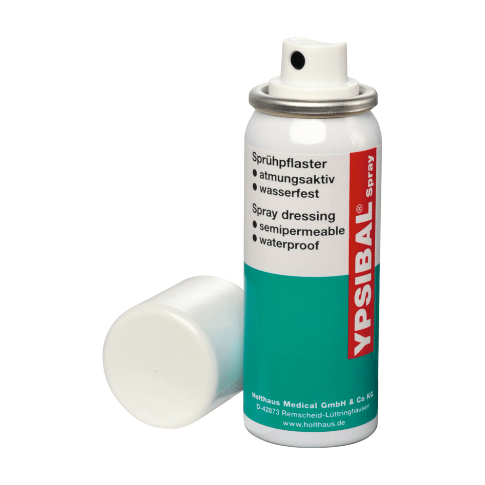 Un spray aerosol Holthaus Ypsibal® Spray, plasture spray - 50 ml de la Holthaus Medical GmbH & Co. KG este prezentat fără capac alb și se sprijină la bază. Textul de pe cutia predominant albă cu secțiuni albastru-verzui și accente roșii indică faptul că este un bandaj spray semipermeabil, impermeabil, respirabil pentru tăieturi și zgârieturi.