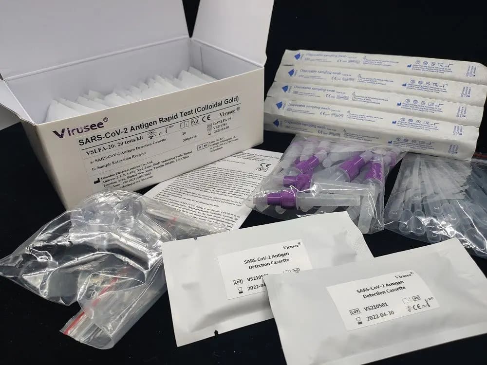 Auf einer schwarzen Oberfläche ist ein Virusee® SARS-CoV-2 Antigen Rapid Test 4in1 Kit von Altruan abgebildet, das mit kolloidaler Goldtechnologie ausgestattet ist. Das Kit enthält Tupfer, Extraktionsröhrchen mit violetten Kappen, Testkassetten und Anleitungsblätter. Die geöffnete Schachtel zeigt Tests im Inneren, die für die Verwendung mit Speichel- oder Tupferproben entwickelt wurden.