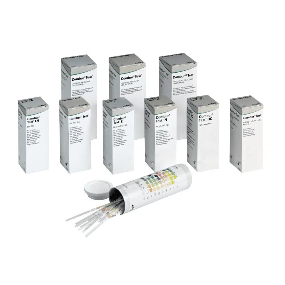 În spatele unui recipient cilindric deschis cu capac se ascund nouă cutii cu inscripția „Combur®“ de la Servoprax GmbH, care conțin fiecare câte 100 de benzi de testare urinară Roche. Pe partea laterală a recipientului este atașat un tabel multicolor, perfect pentru efectuarea unui test rapid.