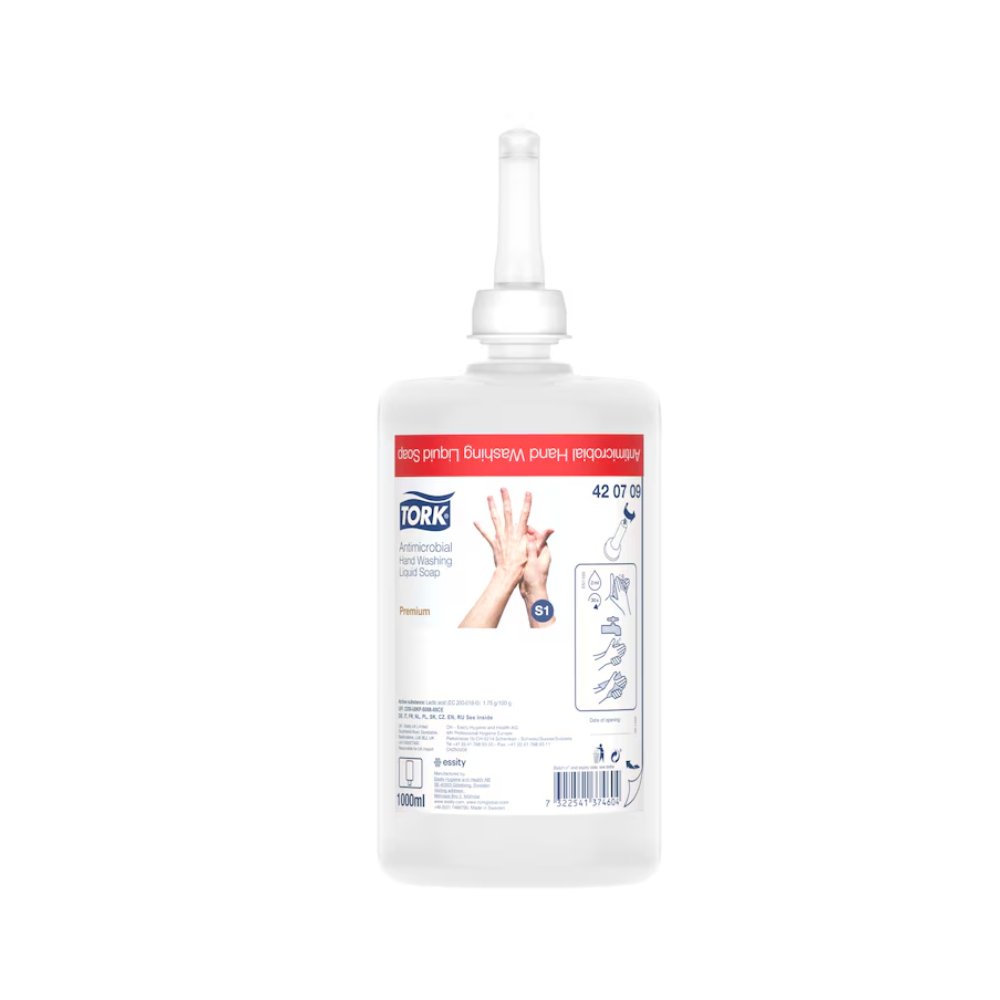 În imagine este un săpun lichid Tork pentru decontaminarea mâinilor, flacon de reumplere pentru distribuitor, cu un duză. Eticheta arată instrucțiuni de utilizare, numele mărcii TORK – Essity Professional Hygiene Germany GmbH și detalii despre produs. Flaconul transparent permite vizualizarea lichidului din interior și astfel subliniază utilizarea în procesarea alimentelor. Eticheta este predominant în culorile roșu și alb.