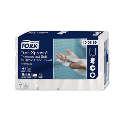 Un pachet de prosoape de hârtie multifold comprimate moi Tork Xpress® Premium H2 cu 2 straturi, fabricate de TORK – Essity Professional Hygiene Germany GmbH, este destinat extragerii individuale a foilor. Ambalajul albastru-alb arată imaginea unei mâini care folosește un prosop moale, subliniind astfel calitatea premium a acestor prosoape de hârtie.