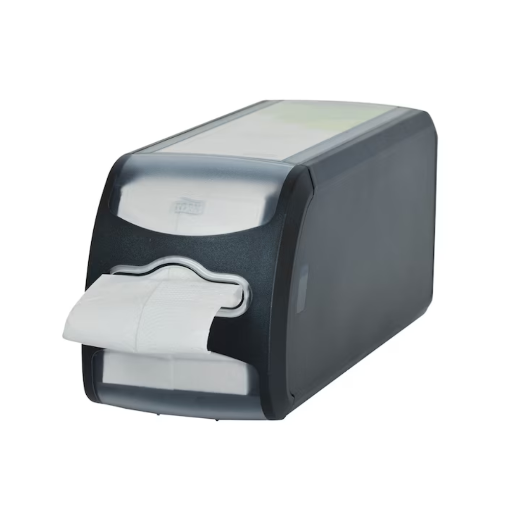 Un dispenser de tejghea din plastic negru pentru șervețele Tork Xpressnap Fit® 272901 de la TORK - Essity Professional Hygiene Germany GmbH are o parte frontală transparentă pe care se vede un teanc de șervețele albe, dintre care unul iese prin deschidere. Designul său permite distribuirea individuală a foilor și este așezat pe un fundal alb.