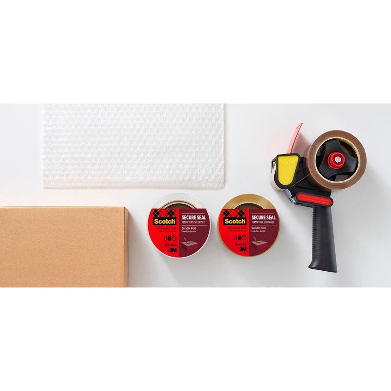 Pe o suprafață albă se află o cutie de carton, folie cu bule, două role de bandă adezivă de ambalare Scotch® pentru o închidere sigură (50 mm x 50 m) de la 3M Deutschland GmbH și un dispenser de bandă adezivă negru-galben.