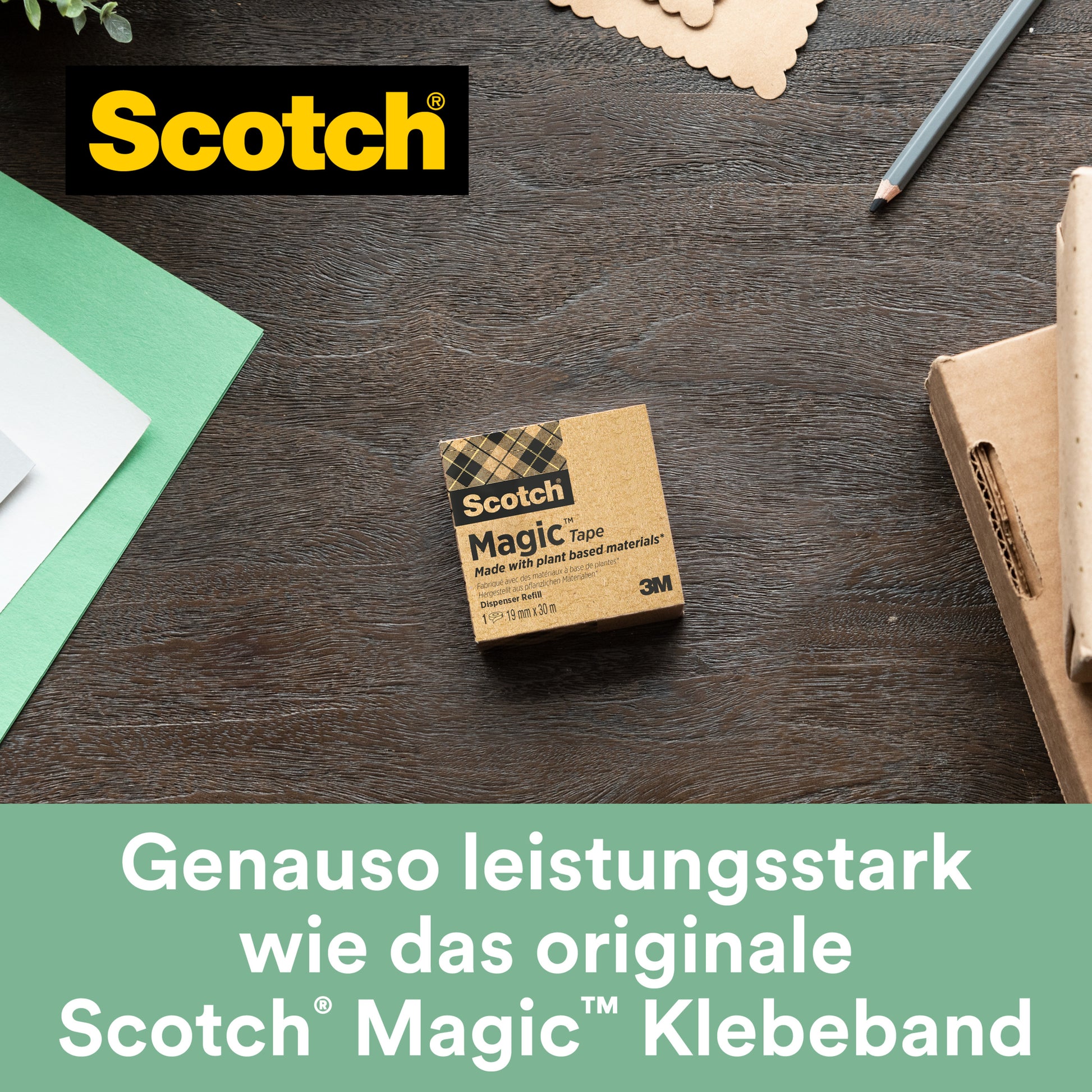Ein Scotch® C38 Tischabroller schwarz mit Scotch® Magic™ Klebeband (19 mm x 33 m, 3 Rollen/Packung, 66 % pflanzlichem Klebstoff) von 3M Deutschland GmbH liegt auf einem Holztisch neben grünem Papier und anderem Bürobedarf.