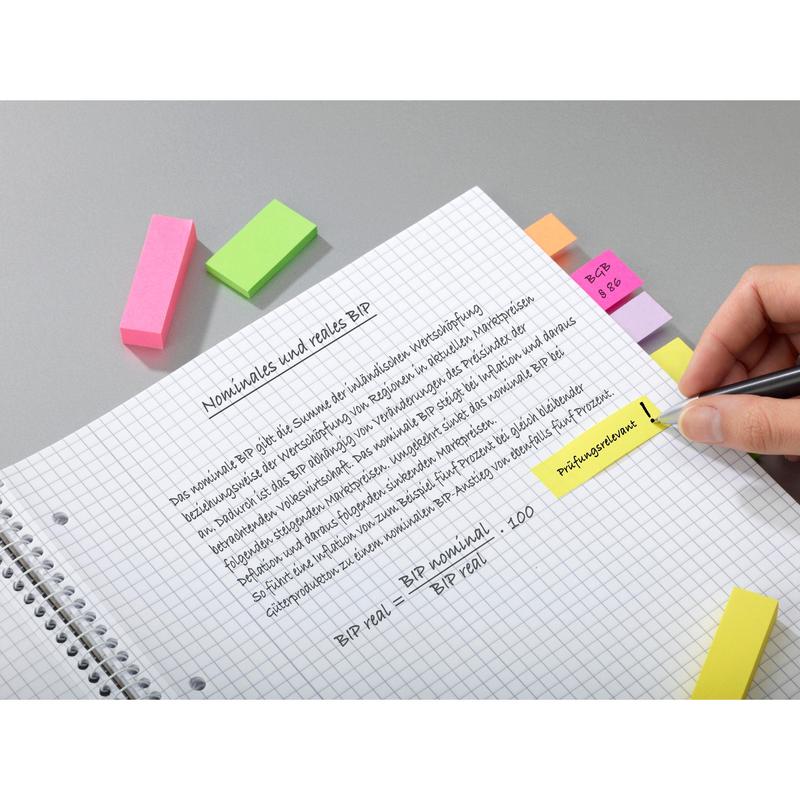 O mână ridică o notiță într-un caiet cu spirală cu text german pe PIB evidențiat. Pe notițe sunt aplicate markere de pagină Post-it® din colecția Energetic (3M Deutschland GmbH, 25 mm x 76 mm, 3 blocuri/pachet) și benzi adezive colorate.